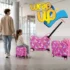 Girl riding kids ride-on luggage set while an adult pulls it through a modern airport